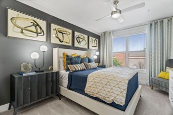 A bedroom with a bed, nightstand, and artwork on the wall.